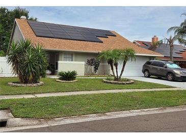 Charming single-story home with well-manicured lawn and solar panels on the roof at 8718 Lindenhurst Pl, Tampa, FL 33634