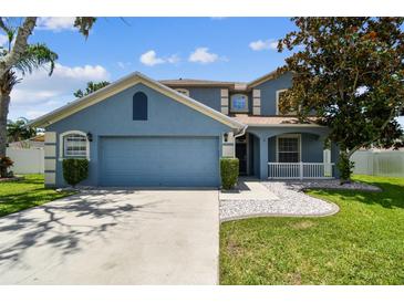 Beautiful blue home with a lush green lawn, complemented by decorative stone accents and fresh landscaping at 1032 Jacob Way, Odessa, FL 33556