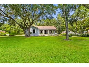 Charming home with a metal roof, covered porch, and lush green lawn at 8600 Shenandoah Run, Wesley Chapel, FL 33544
