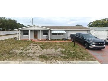 Charming single-story home with a well-maintained lawn and a paved driveway in front at 3243 Umber Rd, Holiday, FL 34691
