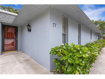 Light gray condo exterior with a black entry door and green shrubbery at 4160 Fruitville Rd # 77, Sarasota, FL 34232