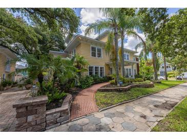 Charming yellow two-story home with lush landscaping, brick path, and a patterned driveway at 635 Bay Ne St, St Petersburg, FL 33701
