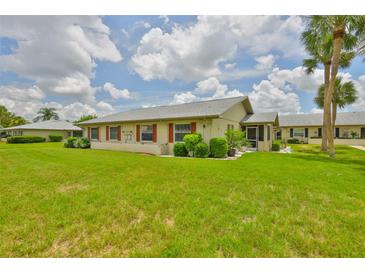 Charming home exterior features a large, well-maintained lawn and mature palm trees, with red shutters on the windows at 1905 Canterbury Ln # 17, Sun City Center, FL 33573
