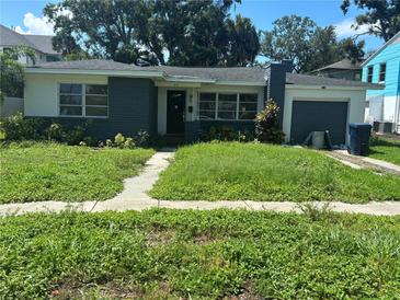 Charming single-story home featuring a brick facade, lush front lawn, and an attached single car garage at 641 Geneva Pl, Tampa, FL 33606