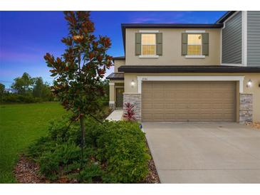 Two-story home boasting a two-car garage, stone accents, and lush landscaping under a twilight sky at 17741 Tawny Malt Pl, Land O Lakes, FL 34638