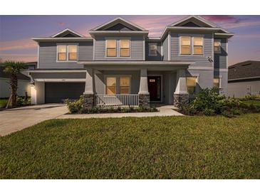 Beautiful two-story home featuring manicured lawn, covered porch with stone accents, and neutral color palette at 2492 Overfalls Pl, Wesley Chapel, FL 33543