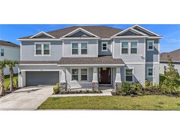 Charming two-story home featuring a manicured lawn, attached garage, and covered entryway at 2492 Overfalls Pl, Wesley Chapel, FL 33543