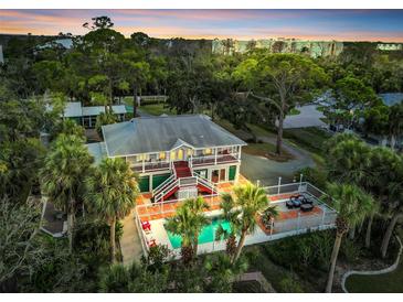 Stunning aerial view of a two-story home with a swimming pool, surrounded by lush greenery and palm trees at 4915 South Rd, New Port Richey, FL 34652