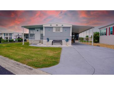 Charming home featuring a covered parking area, bench seating, and well-manicured lawn at 108 W Saint Johns Way # 210, Apollo Beach, FL 33572