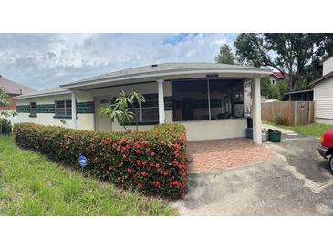Charming single-story home featuring a covered porch, vibrant landscaping, and a brick-paved driveway at 4611 W Mcelroy Ave, Tampa, FL 33611