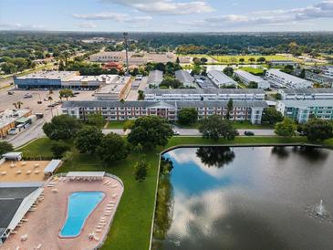 Aerial view of community featuring a large pool, lake with fountain, and several multi-story buildings at 6015 19Th N St # 117, St Petersburg, FL 33714