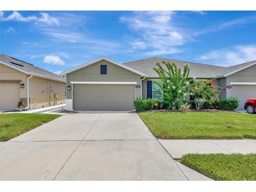 Charming one-story home with a well-manicured lawn, lush landscaping, and a wide driveway at 18164 Turning Leaf Cir, Land O Lakes, FL 34638