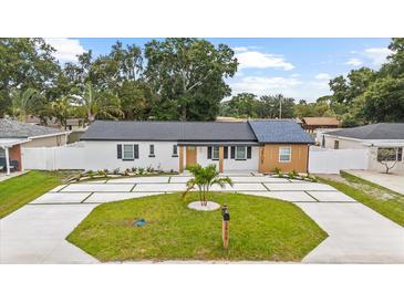 Charming single-story home with a well-manicured lawn and modern driveway at 3909 W Oklahoma Ave, Tampa, FL 33616