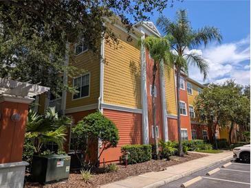 Exterior view of a multi-story condo building with bright colors, landscaping, and palm trees on a sunny day at 4207 S Dale Mabry Hwy # 6212, Tampa, FL 33611