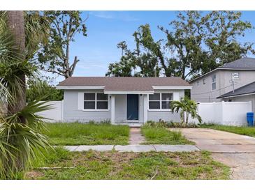Charming single-story home with a blue door, grey facade, mature landscaping, and a driveway at 2311 16Th S Ave, St Petersburg, FL 33712