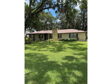 Charming brick home boasts a lush, green lawn and mature trees, complete with a metal roof at 4106 Old Mulberry Rd, Plant City, FL 33567