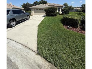 Well-manicured front yard with lush green lawn, mature landscaping, and a two-car garage at 5811 White Oak Bayou Ct, Bradenton, FL 34203