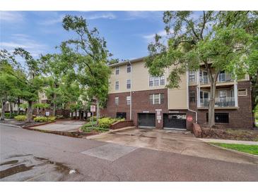 Condo building exterior featuring brick and siding with mature trees and covered parking at 1000 W Horatio St # 129, Tampa, FL 33606