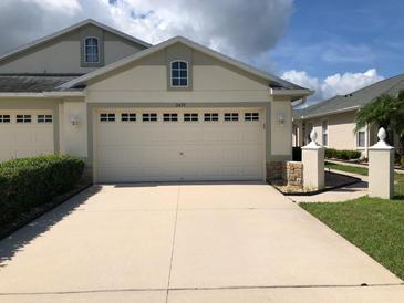 Beige garage and concrete driveway of a one-story home, with white trim and updated windows at 11439 Cambray Creek Loop, Riverview, FL 33579