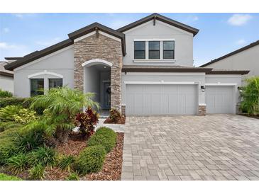 Charming home with a stone accent wall, three-car garage, and a beautiful landscaped yard at 12928 Twin Bridges Dr, Riverview, FL 33579