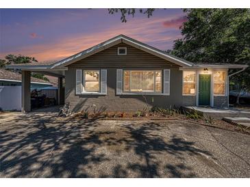 Charming single-story home featuring a covered parking, inviting green door, and lovely front garden at 1432 San Juan Ct, Clearwater, FL 33756