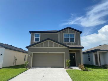 Two-story home featuring gray siding, a two-car garage, well-maintained lawn, and simple landscaping at 35233 White Water Lily Way, Zephyrhills, FL 33541