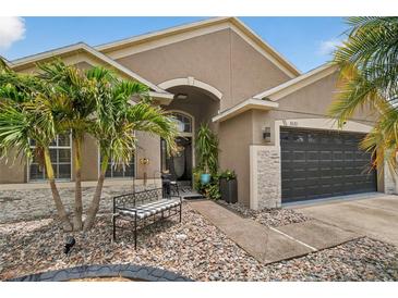 Charming home features stone accents, lush landscaping, and a quaint bench, creating an inviting entrance at 8620 Sandy Plains Dr, Riverview, FL 33578