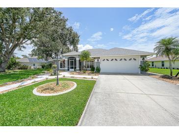 Charming single-story home featuring a well-manicured lawn, mature trees, and a two-car garage at 2226 Charleston Park Dr, North Port, FL 34287