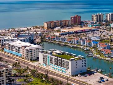 Stunning aerial view of waterfront condos, boat docks, and the beautiful ocean coastline on a sunny day at 400 150Th Ave # 305, Madeira Beach, FL 33708