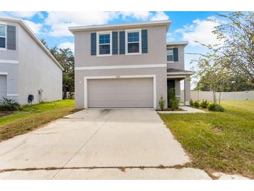 Two-story house with gray siding, a double-car garage, and a neat lawn at 10913 Trailing Vine Dr, Tampa, FL 33610