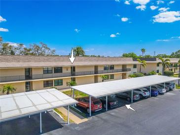 Exterior of condo building featuring carport parking under a blue sky with white clouds at 12300 Vonn Rd # 3204, Largo, FL 33774