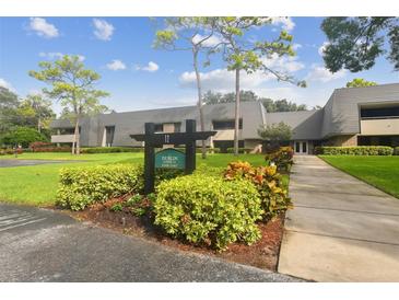 Exterior view of a condo building with landscaping and walkway at 36750 Us Highway 19 N # 12-106, Palm Harbor, FL 34684