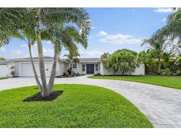 Charming home featuring lush landscaping, a circular driveway, and vibrant green lawn at 170 98Th N Ave, St Petersburg, FL 33702