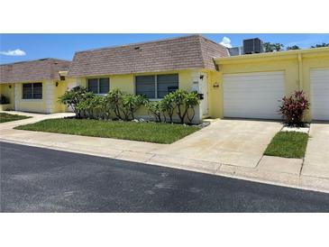 Bright yellow house with a double-car garage and landscaping at 7057 Versailles N # 15, Pinellas Park, FL 33781