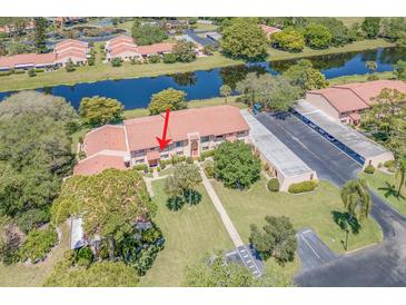 A serene aerial view shows the condo with a tile roof, adjacent to a tranquil lake and convenient parking at 9543 86Th Ave # 9543, Seminole, FL 33777