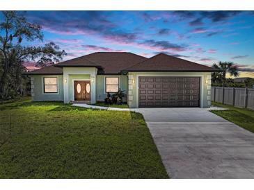 A charming ranch-style home with a two-car garage and manicured lawn at 756 Bowman Ter, Port Charlotte, FL 33953