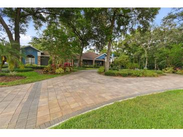 Stunning home with a long, curved brick driveway and lush, mature landscaping, creating great curb appeal at 3204 Polo Pl, Plant City, FL 33566