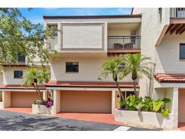 Condo building exterior featuring a two car garage, balcony, and desert landscaping at 240 Windward Psge # 602, Clearwater Beach, FL 33767