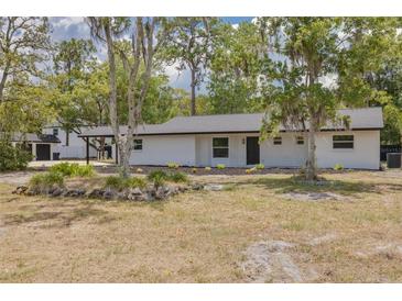 Charming single-story home featuring a fresh white exterior, dark roof, and well-maintained landscaping at 7414 Van Dyke Rd, Odessa, FL 33556