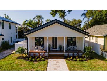 Charming single-story home featuring a well-manicured lawn and inviting front porch with seating area at 316 11Th N Ave, St Petersburg, FL 33701