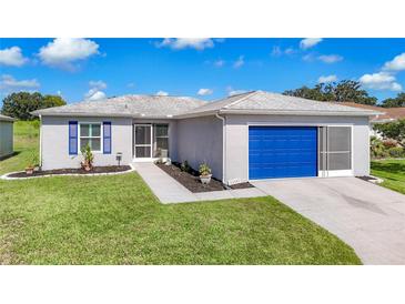 Single-Gathering home with gray exterior, blue garage door, and landscaped yard at 11247 Corey Pavin Ln, San Antonio, FL 33576