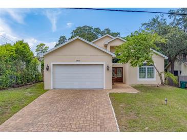 Two-story home with a white garage door and brick driveway at 1950 Lillian Ave, Tarpon Springs, FL 34689