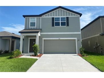 Two-story house with gray siding, two-car garage, and a manicured lawn at 35182 White Water Lily Way, Zephyrhills, FL 33541