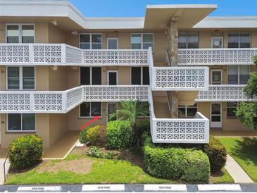 Tan condo building with block white railings, stairs, and neatly trimmed landscaping, and visitor parking at 5095 Bay Ne St # 114, St Petersburg, FL 33703