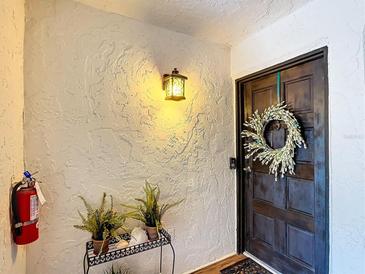 Inviting condo entry with dark wood door, wreath, light fixture, and potted plants at 225 Country Club Dr # E246, Largo, FL 33771