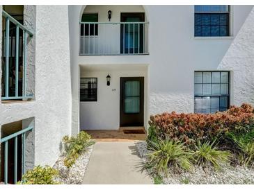 Condo building exterior, unit 115, featuring a walkway and landscaping at 1730 Manasota Beach Rd # 115, Englewood, FL 34223