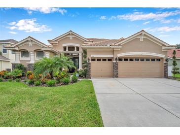 Tan two-story house with three car garage and manicured lawn at 11519 Belle Haven Dr, New Port Richey, FL 34654