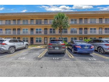 Exterior view of condo building with parking in front at 6400 46Th N Ave # 117, Kenneth City, FL 33709