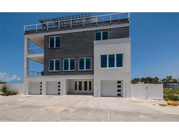 Modern three-story home showcasing a sleek design with a rooftop deck and an attached three-car garage at 2 4Th Ave, Indian Rocks Beach, FL 33785