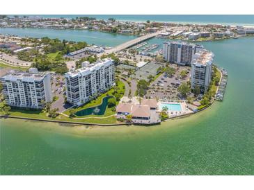 Aerial view of waterfront community with pool, tennis courts, and lush landscaping at 9415 Blind Pass Rd # 803, St Pete Beach, FL 33706